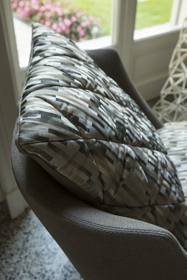 The comfortable cushioning and curved armrests of this modern armchair make it the perfect spot for relaxation and comfort