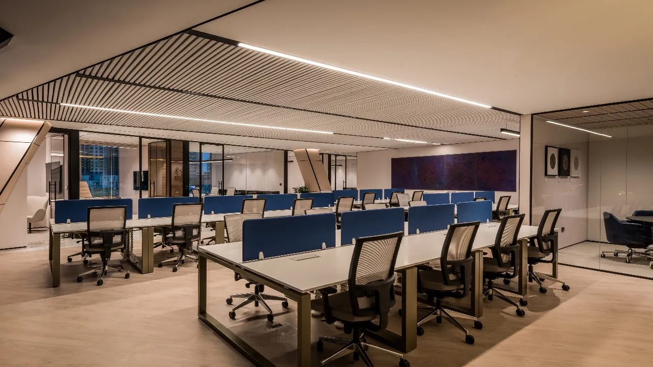 Main working area in an office wth workstation and meeting room with glass partitions along the wall